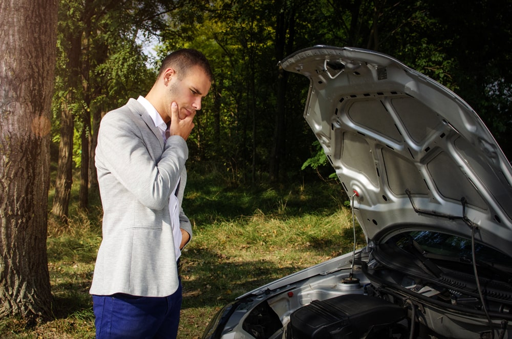 man standing road by broken car thinking how fix it